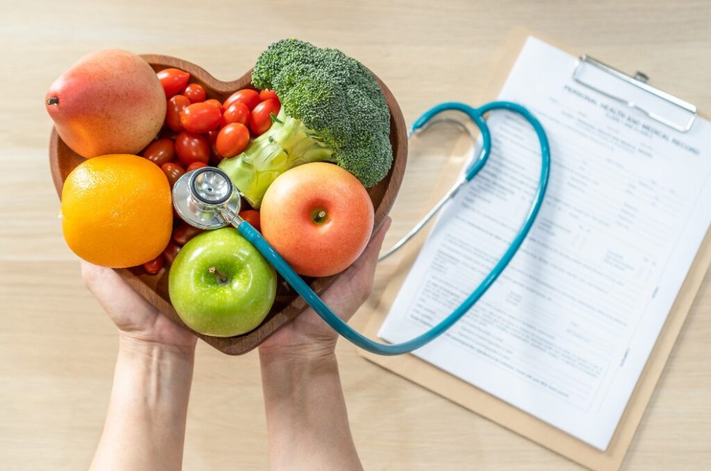 Nahrhafte Lebensmittel für die Herzgesundheit durch cholesterinbewusste Ernährung und gesunde Ernährung mit frischem Obst und Gemüse in einer herzförmigen Schale – empfohlen von Ernährungsberatern und Ärzten für das Wohlbefinden der Patienten.